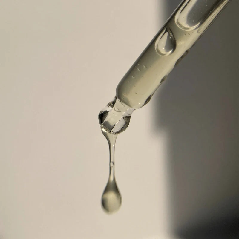 Pretty Picks skincare serum dropper releasing a clear hydrating liquid against a neutral background.